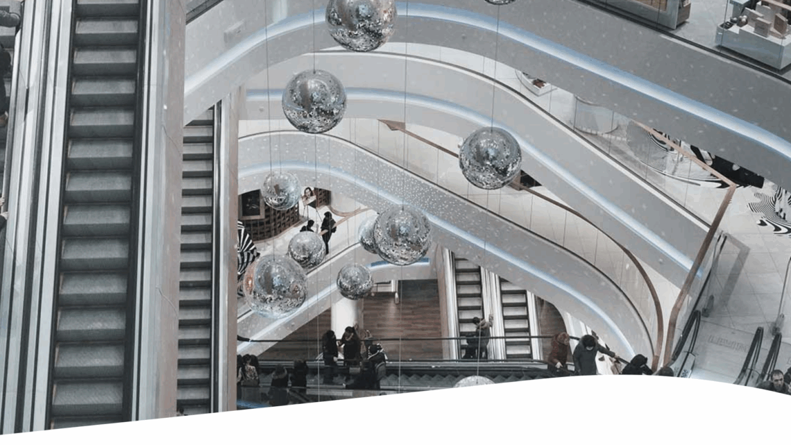 A group of people going up the escalator at an indoor mall.